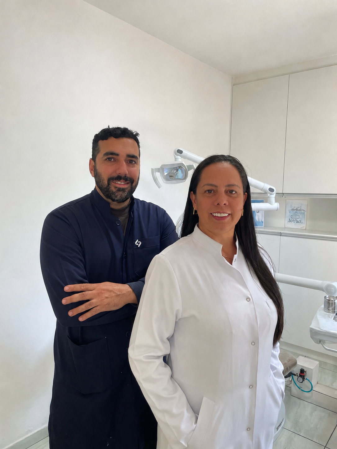 Dr. Anderson e Dra. Juliana, especialistas da J&M Odontologia, em jaleco no ambiente clínico